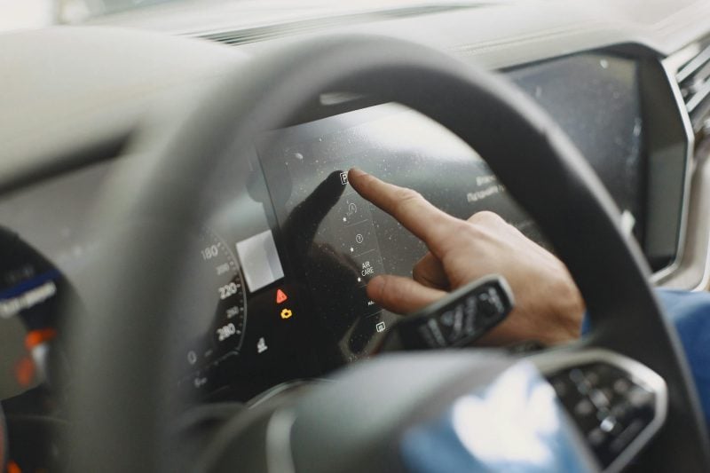 Close-up of a hand interacting with a car's touchscreen. Modern technology and driving interface.