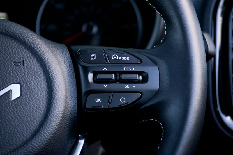 Detailed view of a car steering wheel with physical control buttons, showcasing modern design and functionality.